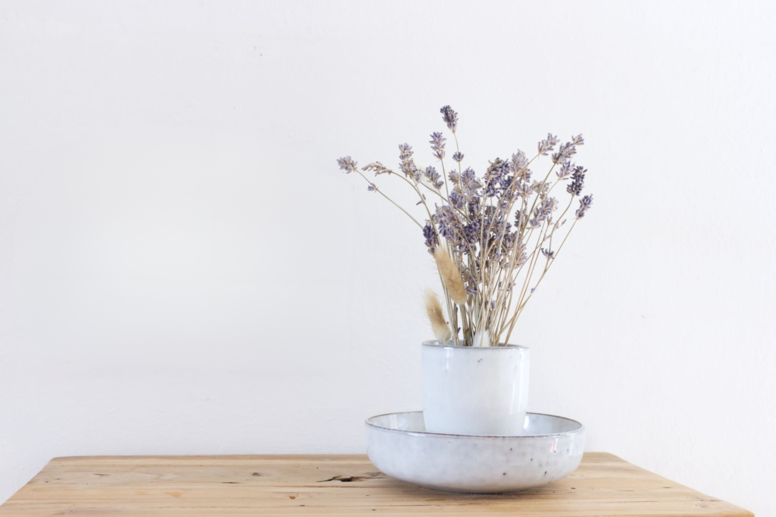 Minimalist Scandinavian home accent with dried lavender in a ceramic vase on a wooden table, symbolizing natural simplicity and calm living.
