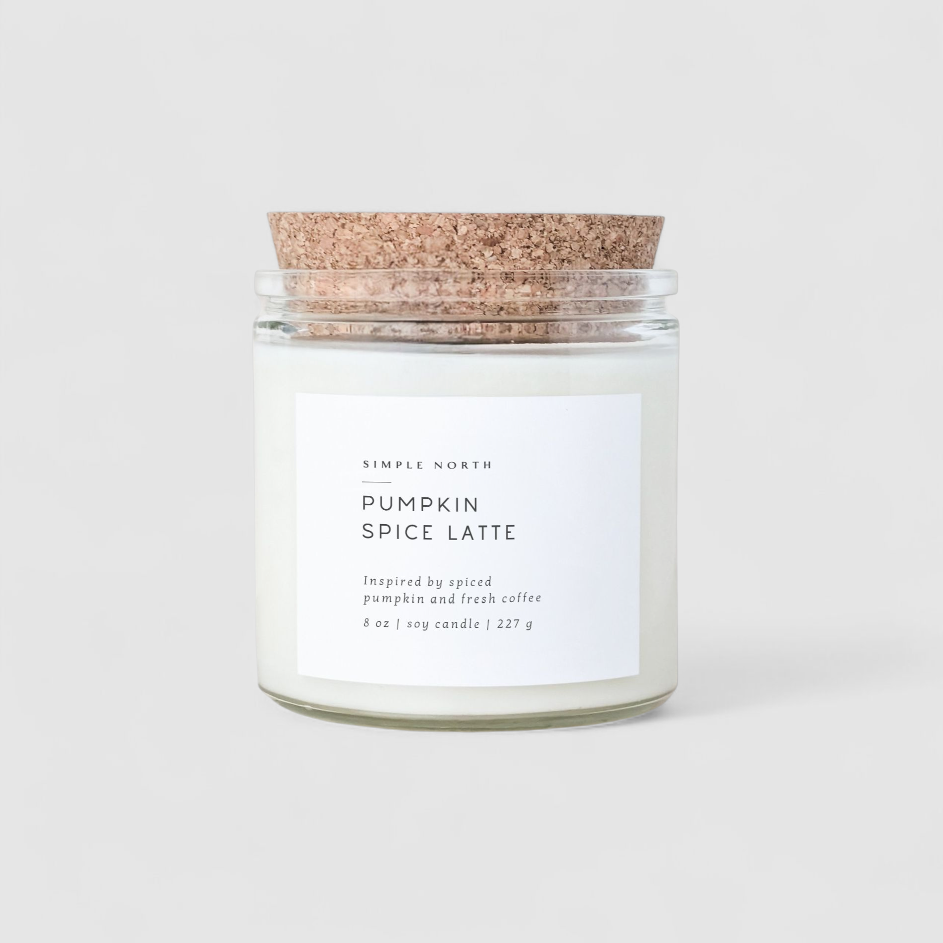 Glass candle with cork lid labeled 'Pumpkin Spice Latte' on a white background